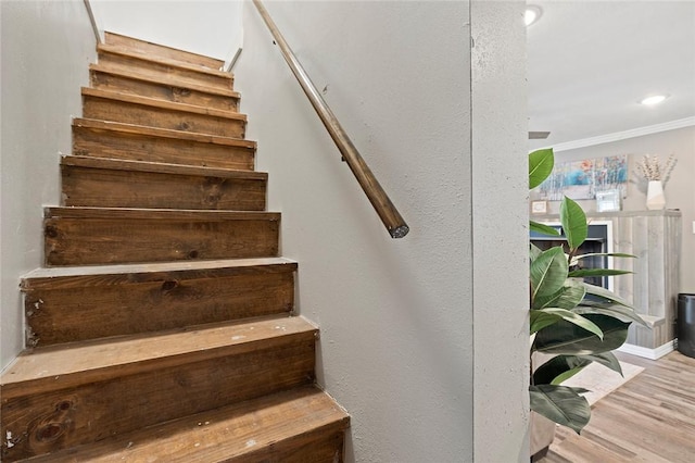 staircase featuring hardwood / wood-style floors and ornamental molding