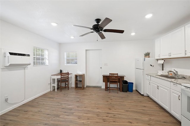 kitchen featuring white appliances, a wall mounted AC, sink, light hardwood / wood-style floors, and white cabinetry