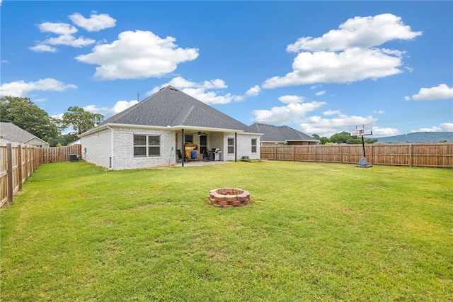 back of property featuring a fire pit, central AC unit, a patio area, and a lawn