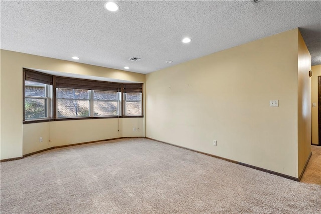 carpeted empty room featuring a textured ceiling