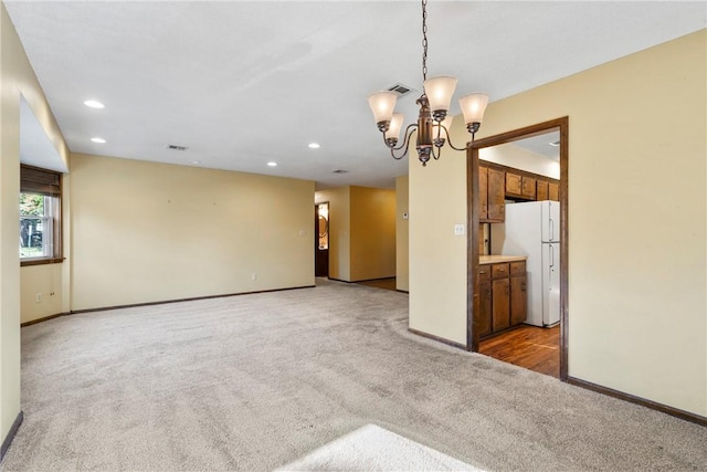 carpeted spare room featuring an inviting chandelier