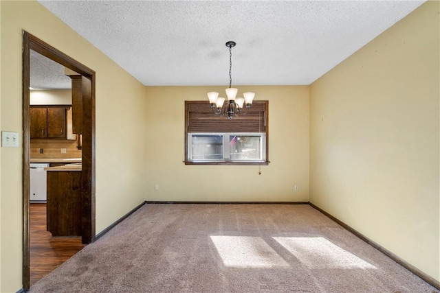 carpeted spare room with a textured ceiling and a chandelier