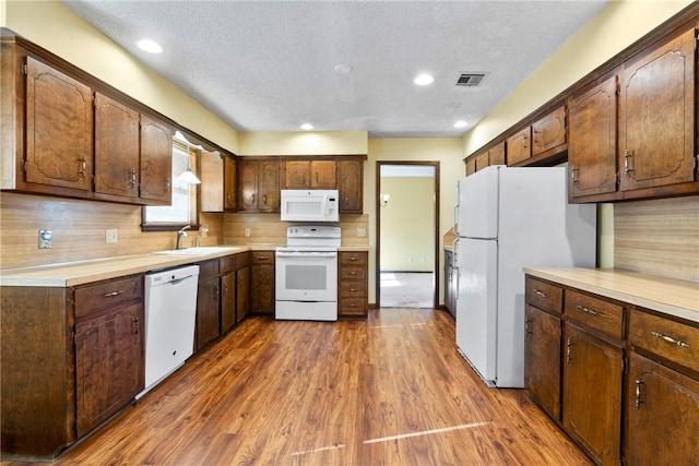 kitchen with sink, tasteful backsplash, dark hardwood / wood-style floors, a textured ceiling, and white appliances