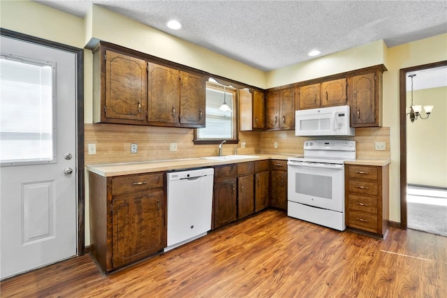 kitchen featuring white appliances, sink, dark hardwood / wood-style floors, tasteful backsplash, and a chandelier