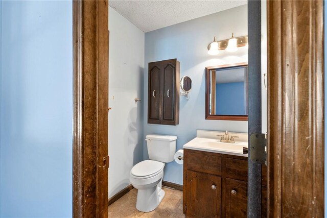 bathroom with tile patterned floors, vanity, a textured ceiling, and toilet