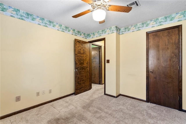 unfurnished bedroom with a textured ceiling, light colored carpet, and ceiling fan