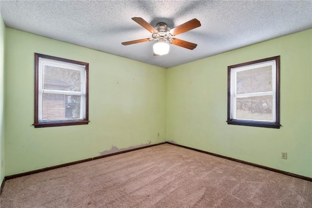 carpeted spare room with ceiling fan, plenty of natural light, and a textured ceiling