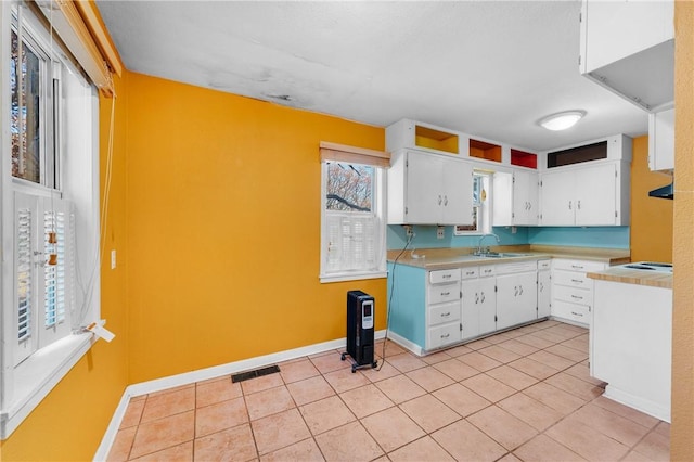 kitchen with white cabinets, light tile patterned floors, and sink