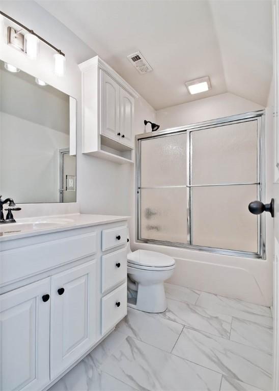 full bathroom with shower / bath combination with glass door, vanity, vaulted ceiling, and toilet