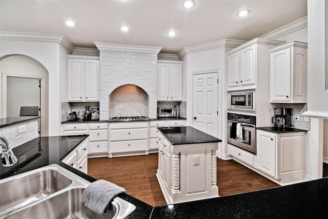 kitchen with backsplash, white cabinets, dark wood-type flooring, and appliances with stainless steel finishes