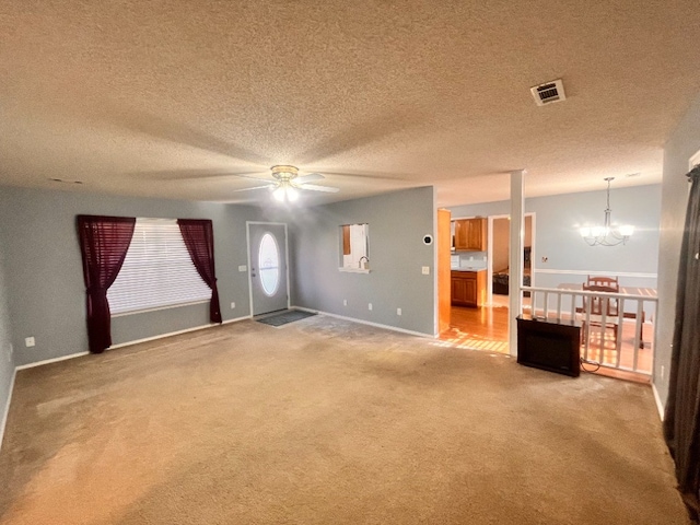 unfurnished living room featuring carpet flooring, a textured ceiling, and ceiling fan with notable chandelier