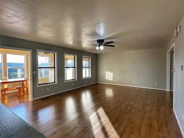 empty room featuring plenty of natural light, dark hardwood / wood-style floors, and ceiling fan