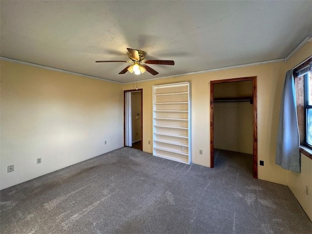 unfurnished bedroom featuring crown molding, dark carpet, and ceiling fan