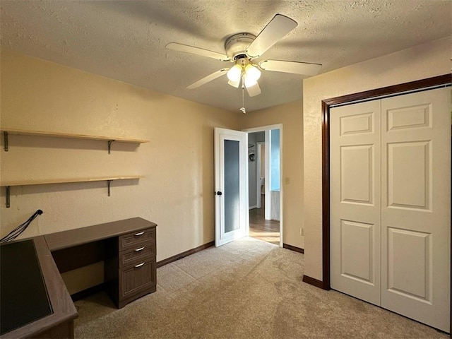 unfurnished office with ceiling fan, light colored carpet, and a textured ceiling