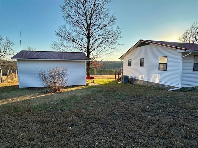 property exterior at dusk with central AC unit and a lawn