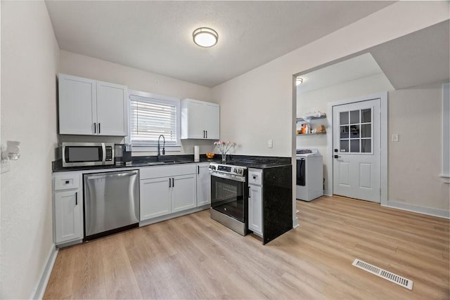 kitchen featuring white cabinets, sink, stainless steel appliances, and washing machine and clothes dryer