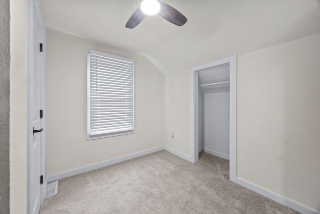 unfurnished bedroom with light carpet, a closet, vaulted ceiling, and ceiling fan