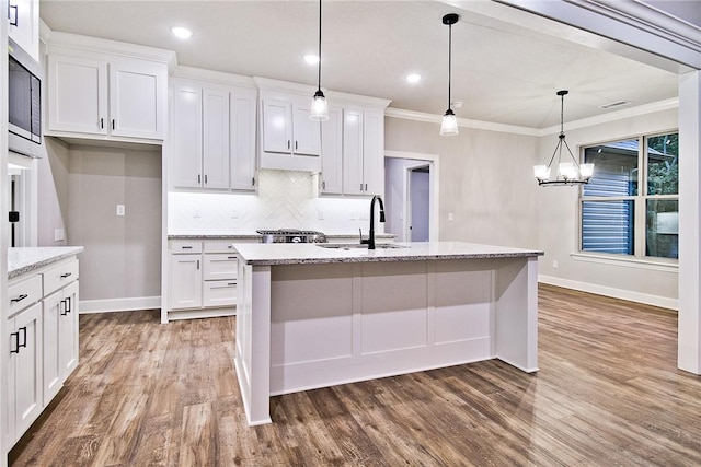 kitchen with white cabinets, hardwood / wood-style floors, decorative light fixtures, and ornamental molding