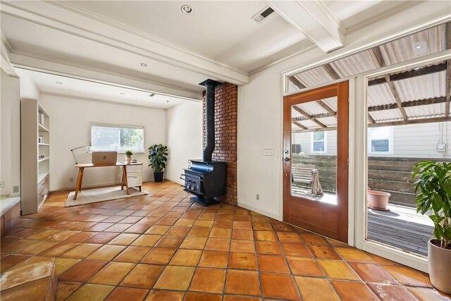 doorway featuring ornamental molding, a wood stove, tile patterned floors, and beam ceiling