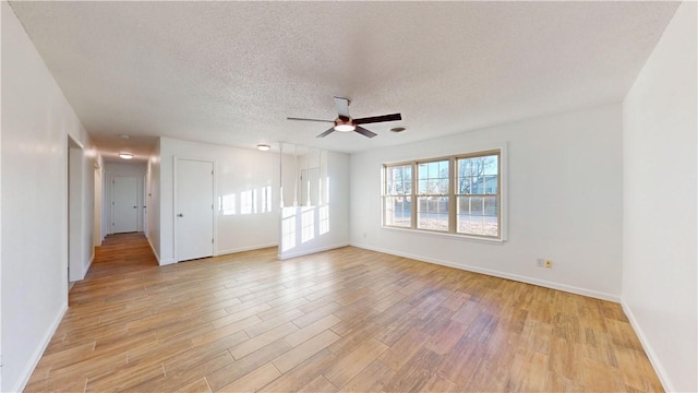 empty room with ceiling fan, light hardwood / wood-style floors, and a textured ceiling