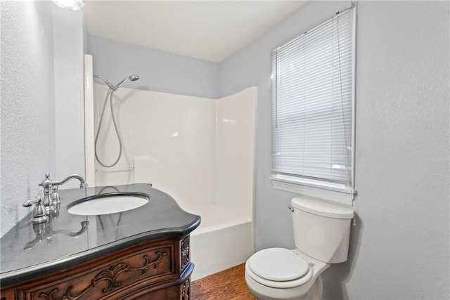 full bathroom with washtub / shower combination, hardwood / wood-style floors, vanity, and toilet