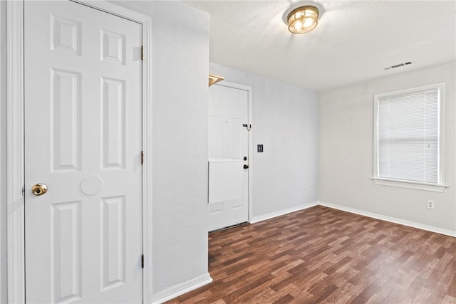 unfurnished room featuring a textured ceiling and dark wood-type flooring