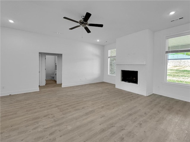 unfurnished living room featuring a fireplace, light hardwood / wood-style flooring, and ceiling fan