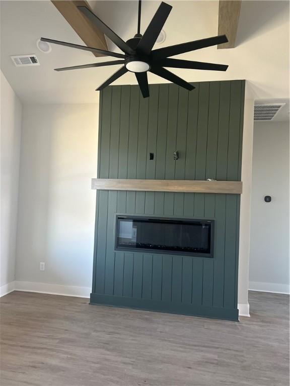 details featuring wood-type flooring, a large fireplace, and ceiling fan