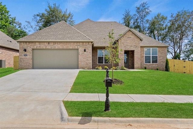 view of front of house featuring a garage, a front lawn, and central air condition unit