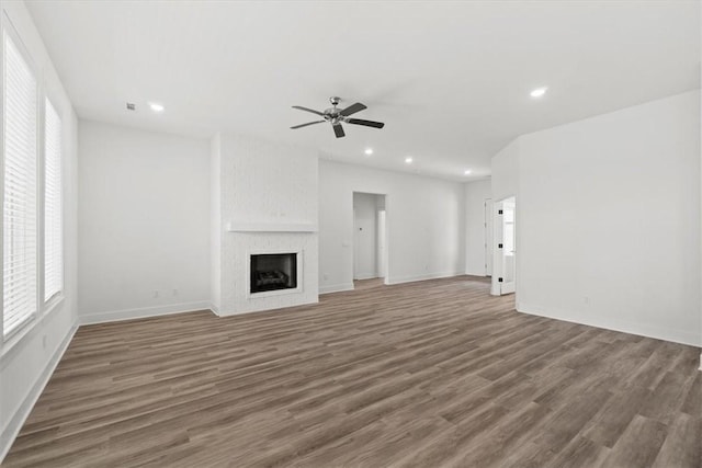 unfurnished living room featuring a fireplace, dark hardwood / wood-style flooring, and ceiling fan