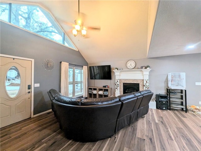 living room featuring a tile fireplace, dark hardwood / wood-style flooring, high vaulted ceiling, and ceiling fan