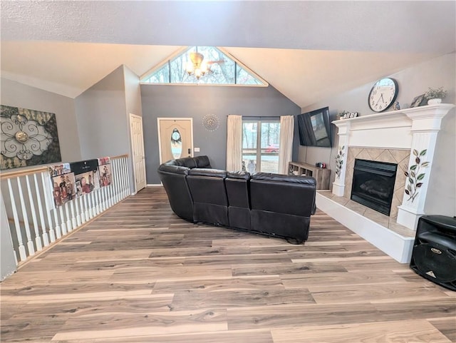 living room featuring a fireplace, high vaulted ceiling, a notable chandelier, and hardwood / wood-style flooring