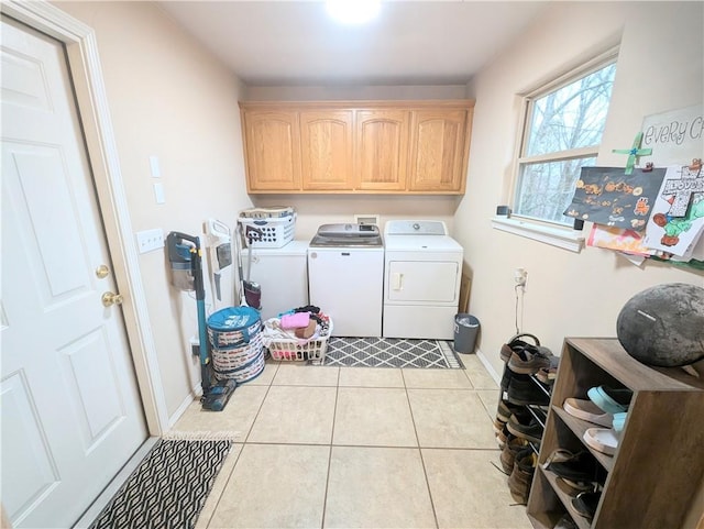 clothes washing area with washer and clothes dryer, light tile patterned floors, and cabinets