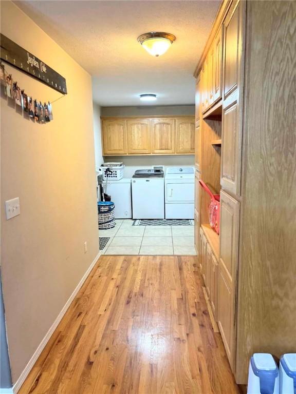 laundry room featuring cabinets, light hardwood / wood-style flooring, and washer and dryer