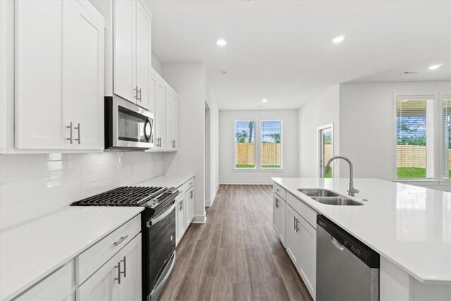 kitchen featuring sink, dark wood-type flooring, backsplash, white cabinets, and appliances with stainless steel finishes