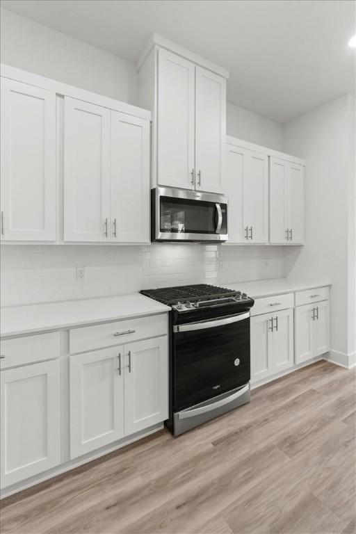 kitchen with white cabinets, stainless steel appliances, and light hardwood / wood-style floors