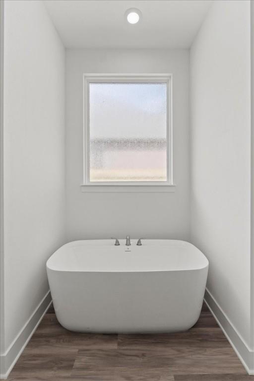 bathroom with a bathtub and hardwood / wood-style flooring