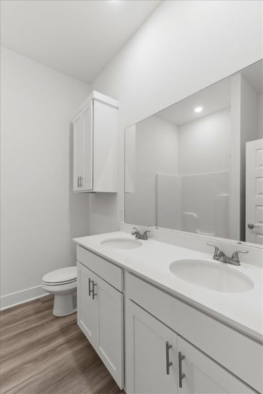 bathroom featuring a shower, wood-type flooring, vanity, and toilet