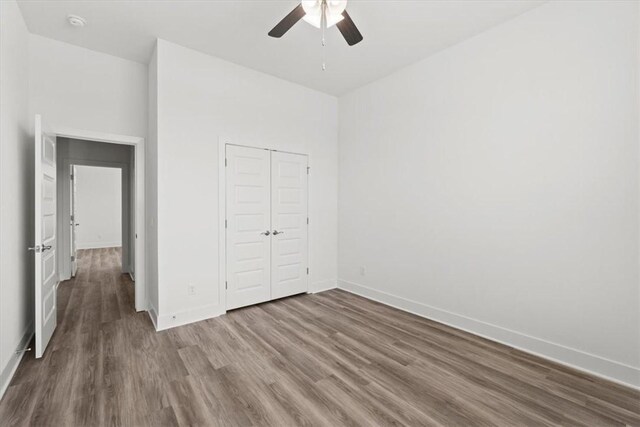 unfurnished bedroom featuring ceiling fan, wood-type flooring, and a closet