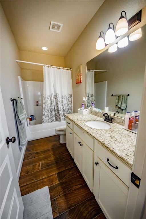 full bathroom featuring hardwood / wood-style floors, vanity, shower / tub combo, and toilet