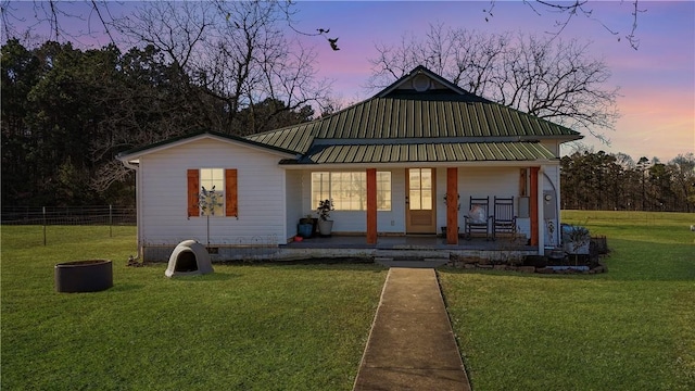 back house at dusk with a porch and a yard