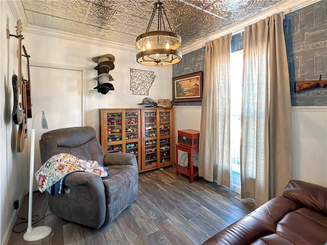 living area featuring crown molding, dark hardwood / wood-style floors, and an inviting chandelier