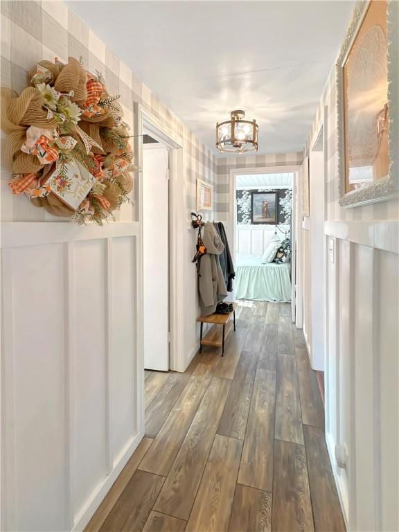 corridor with an inviting chandelier and hardwood / wood-style flooring