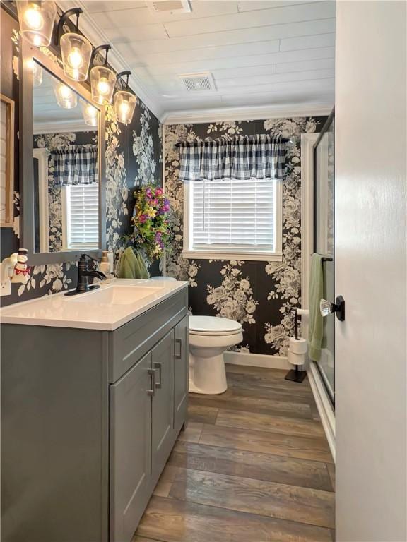 bathroom featuring crown molding, hardwood / wood-style floors, toilet, vanity, and a shower with shower door