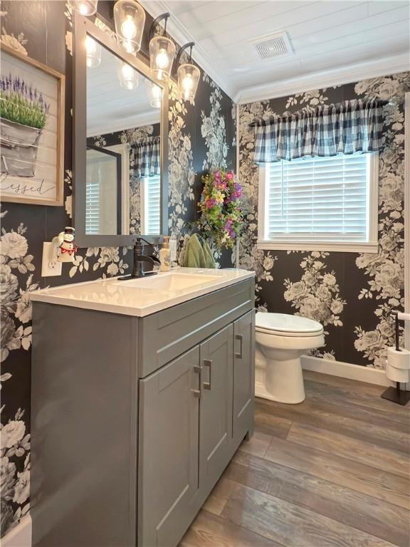 bathroom with hardwood / wood-style floors, a healthy amount of sunlight, toilet, and crown molding