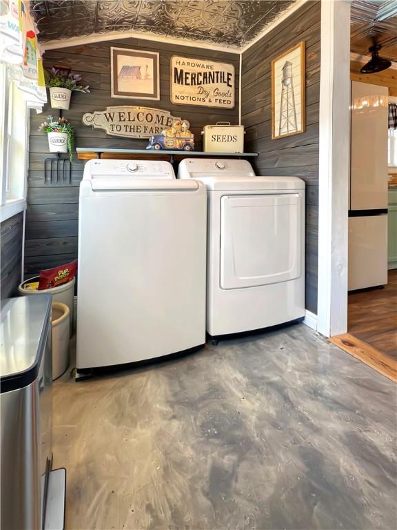 clothes washing area featuring wood walls and washer and dryer