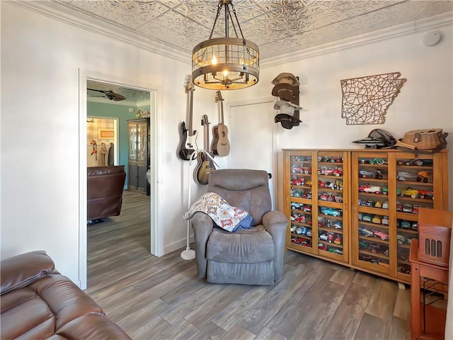 sitting room featuring ceiling fan with notable chandelier, hardwood / wood-style flooring, and crown molding