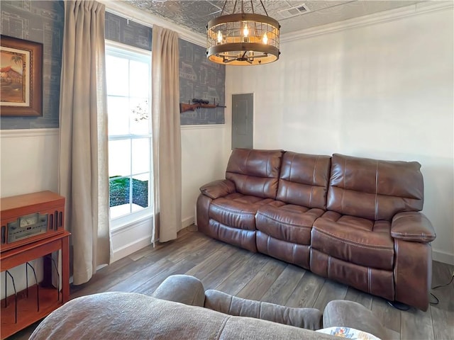 living room with electric panel, hardwood / wood-style floors, a notable chandelier, and ornamental molding