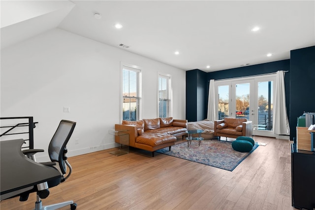 living room with vaulted ceiling, plenty of natural light, french doors, and light wood-type flooring