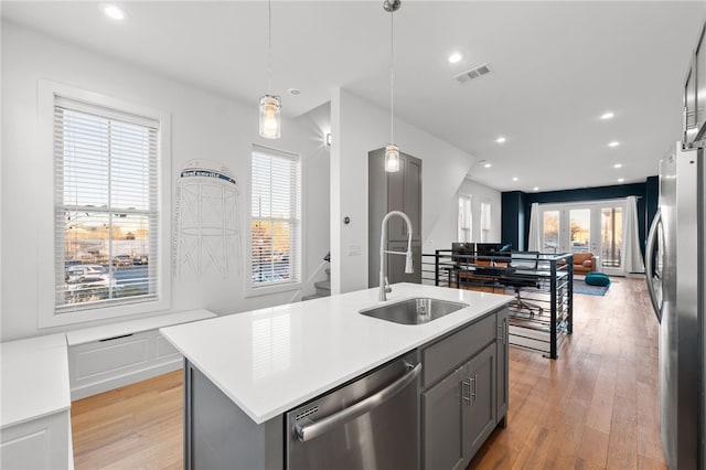 kitchen with a kitchen island with sink, a healthy amount of sunlight, and appliances with stainless steel finishes